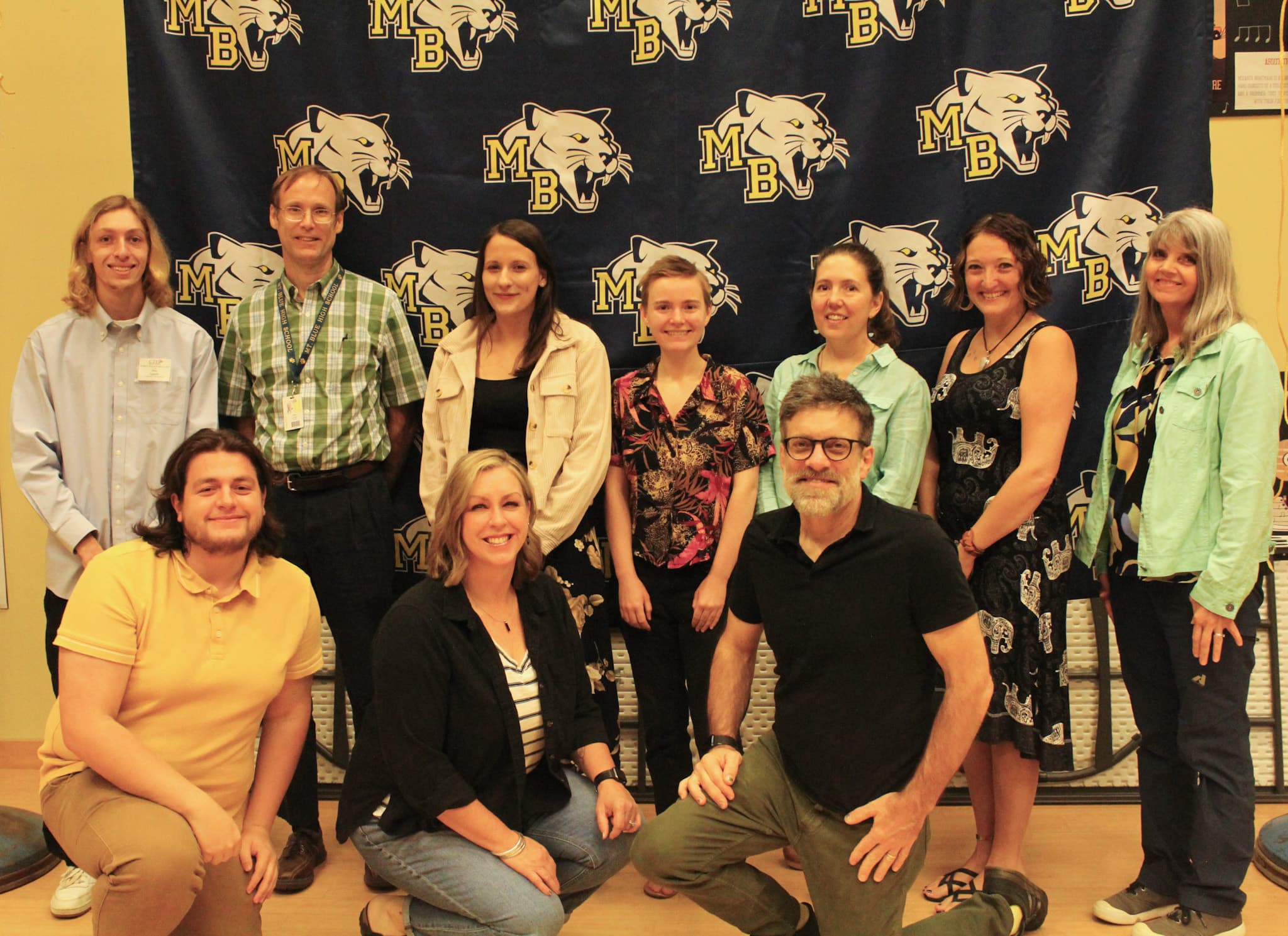 Ten people from the english department pose in front of a Mt. Blue backdrop